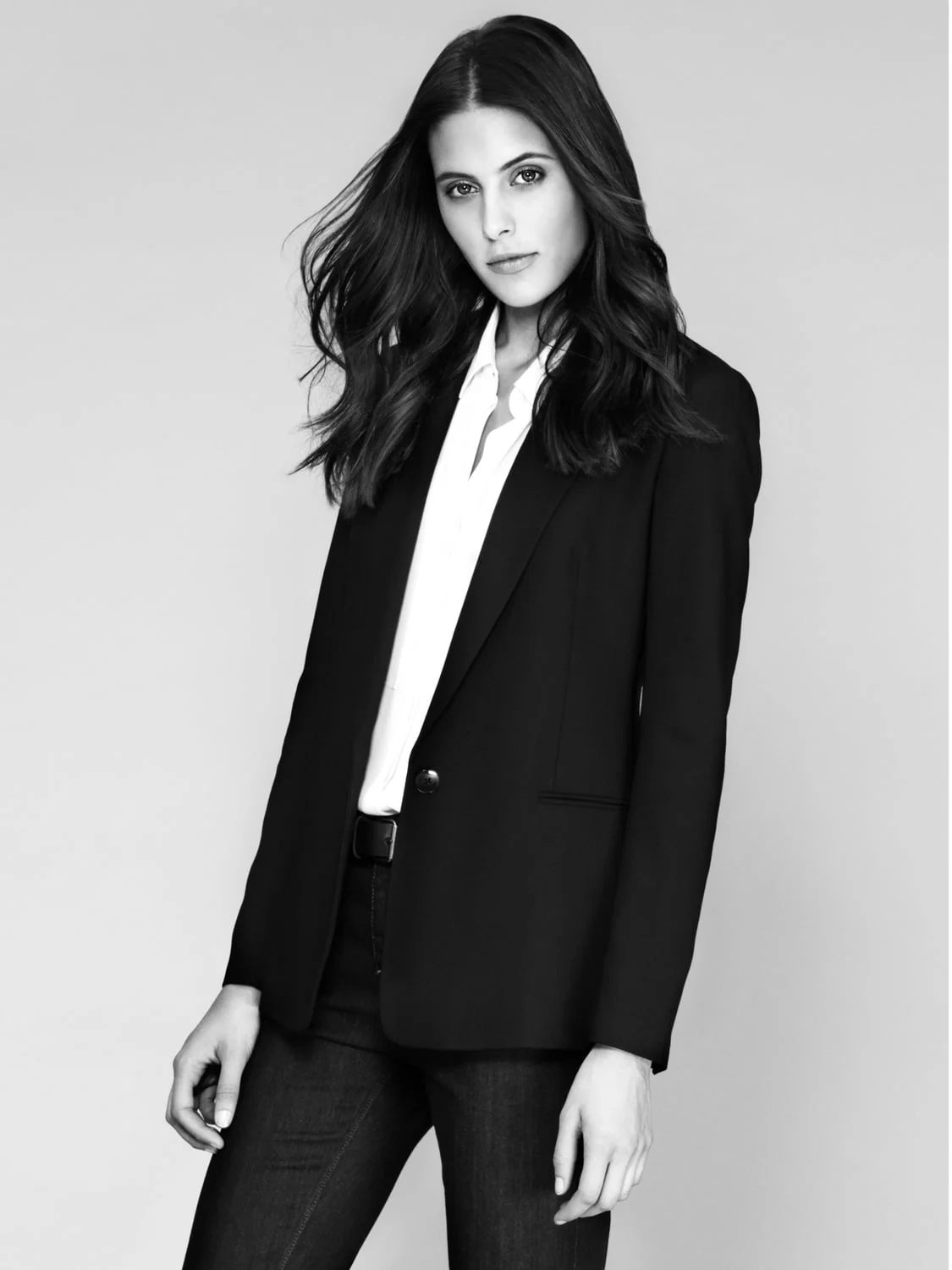 Black-and-white portrait of Sonya Gorelova in a black blazer, white shirt and dark jeans against a pale backdrop.