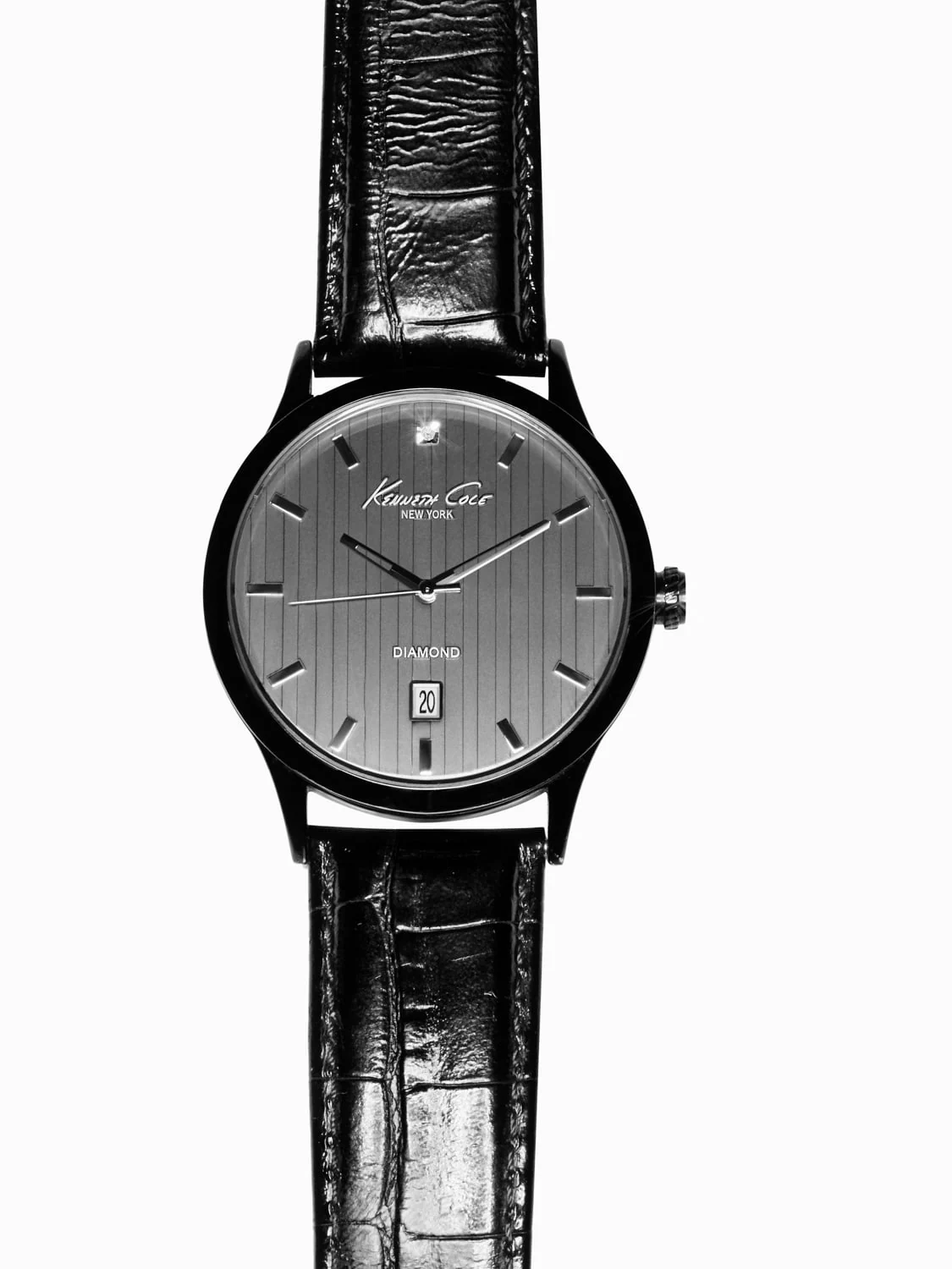 Black wristwatch with a pinstriped grey dial, diamond accent and croc-embossed leather strap on white, for Kenneth Cole.