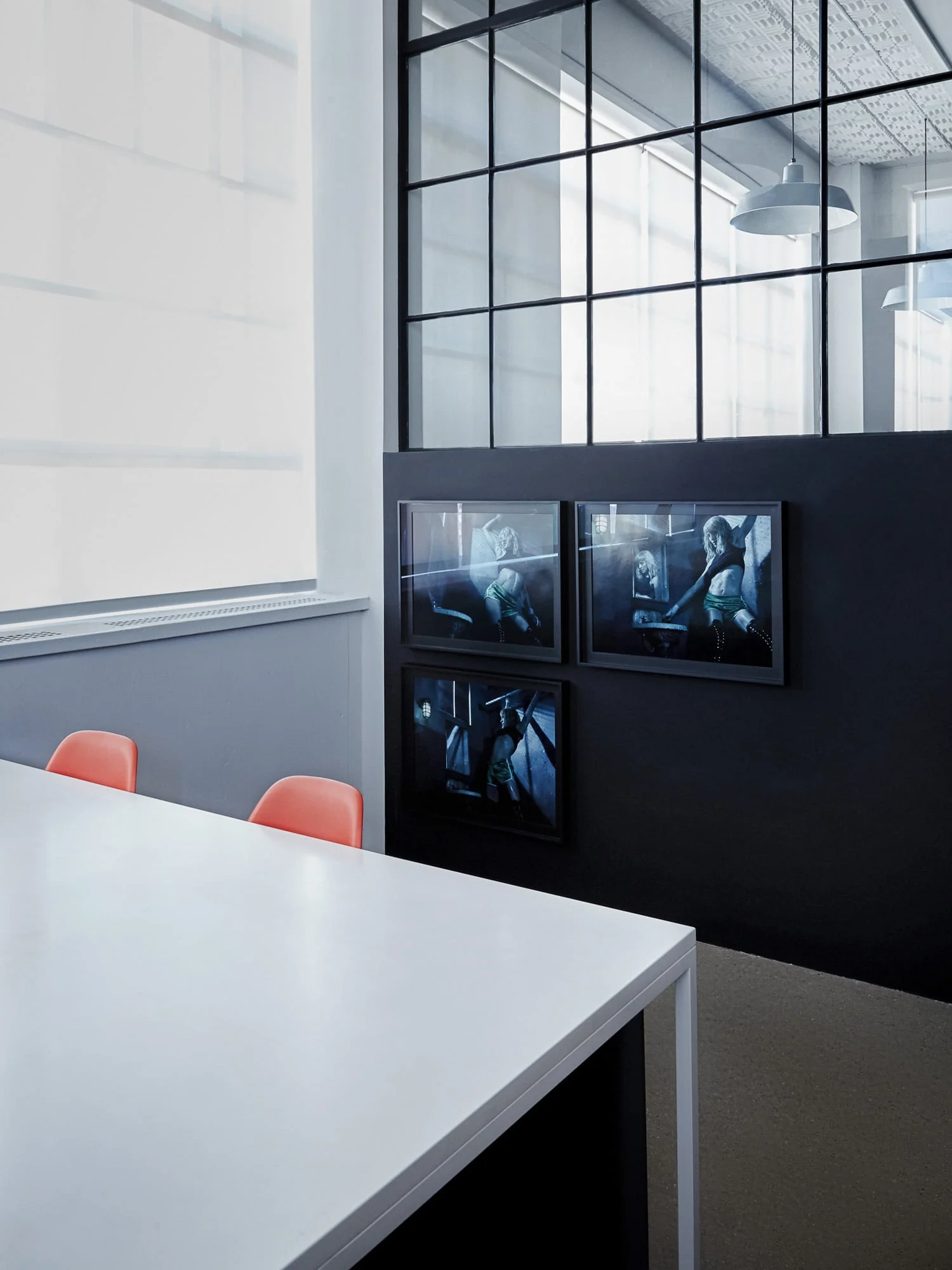 Office with white table, orange chairs, and three framed blue-toned photographs on a dark wall, for Giovanni Bianco.