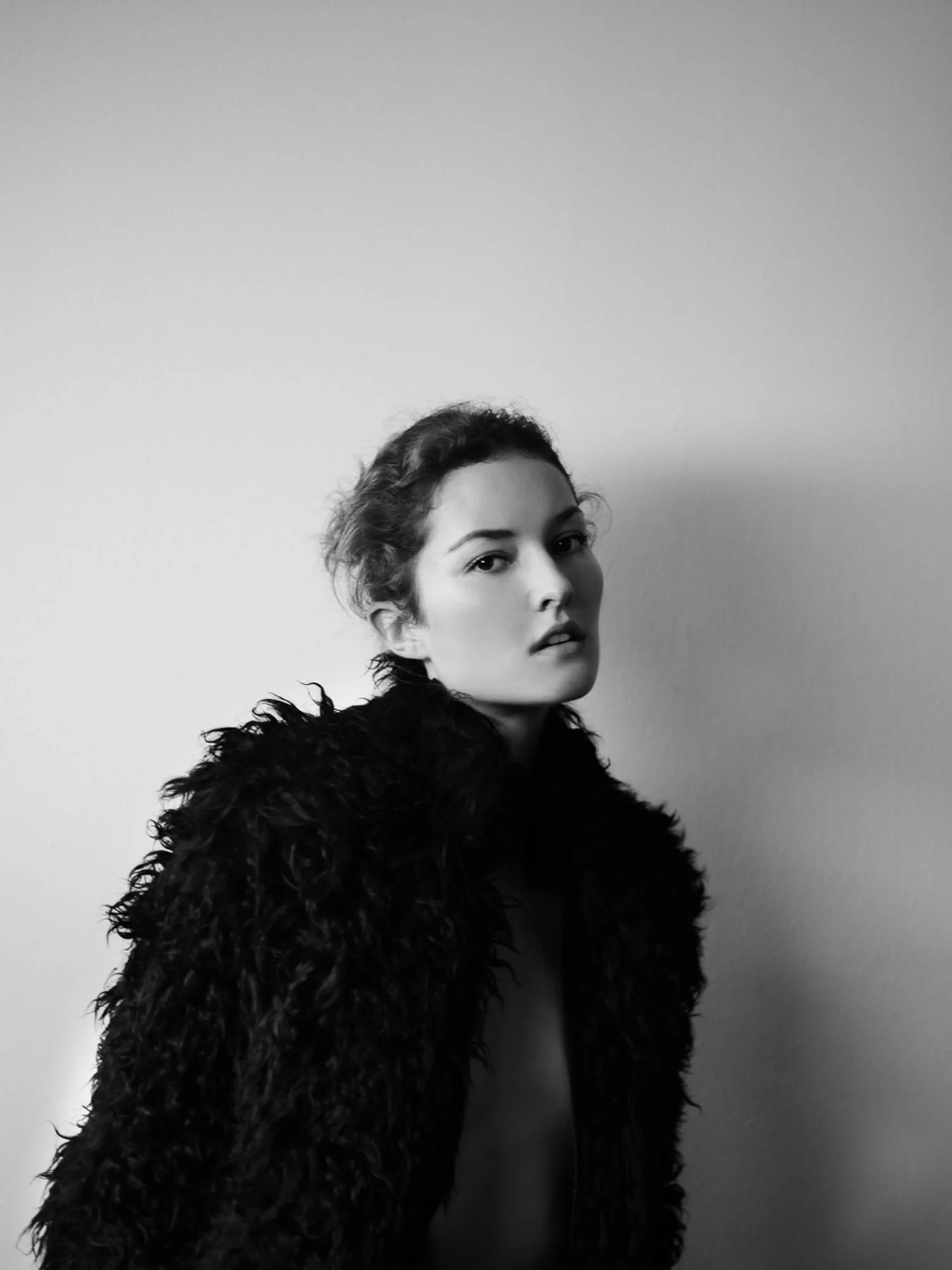 Black and white portrait of Solange Wilvert in a shaggy black coat, hair pinned up, against a plain wall.