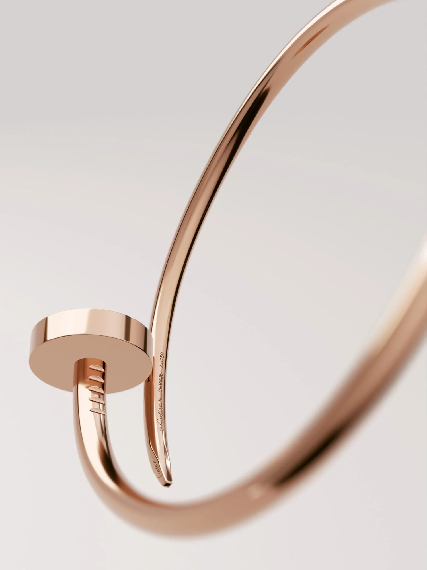Close-up of a rose gold Juste un Clou nail bracelet curving against a soft grey background, for Cartier.