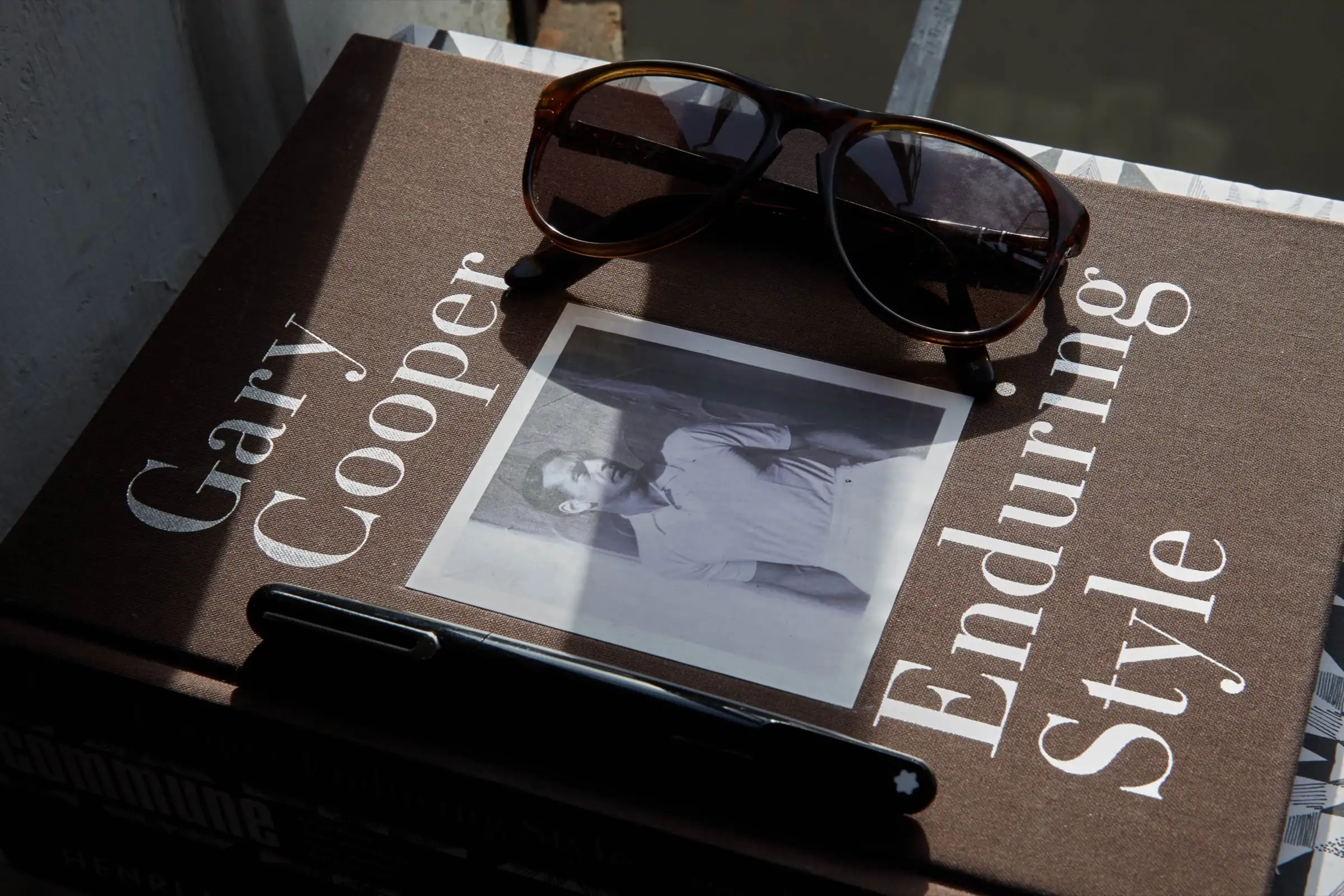 Gary Cooper Enduring Style book in sunlight, topped with tortoiseshell sunglasses and a black fountain pen.