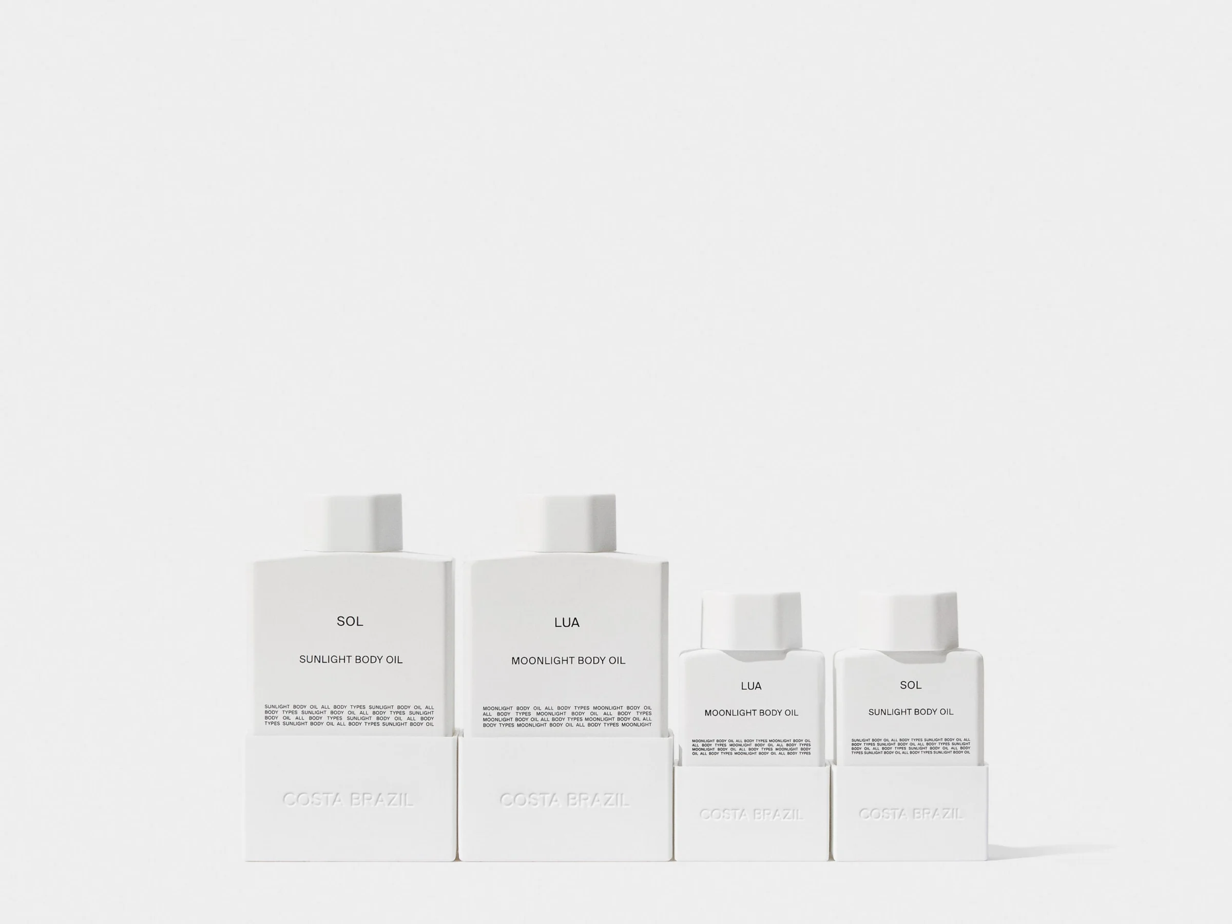 Four white bottles of Sol sunlight and Lua moonlight body oil in two sizes on a white background, for Costa Brazil.