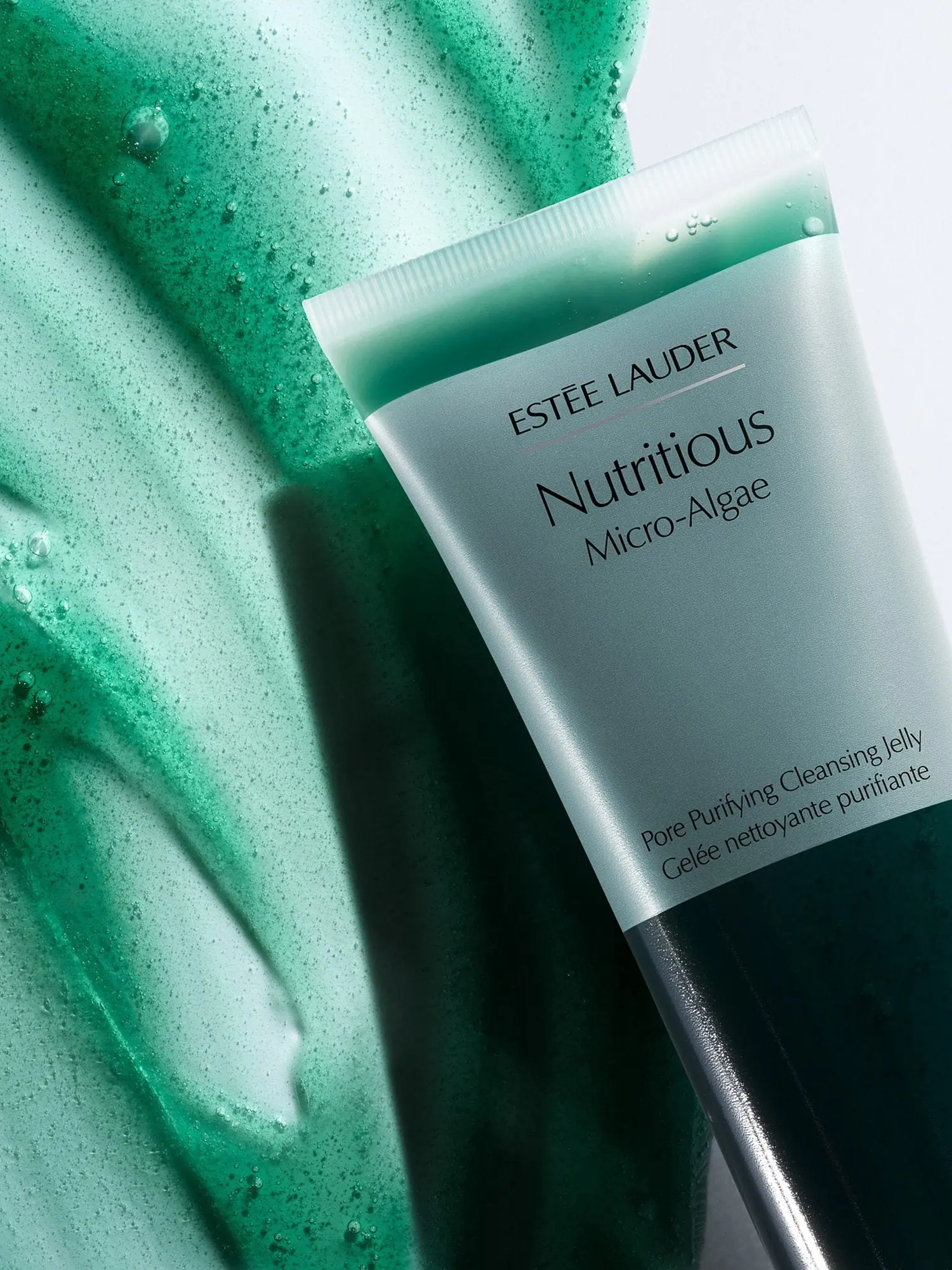 Nutritious Micro-Algae cleansing jelly tube resting on a smear of green textured gel, still life, for Estée Lauder.